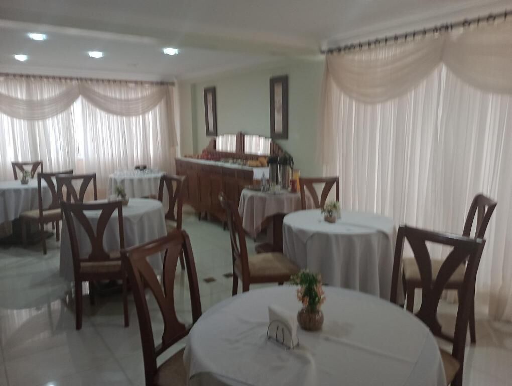 A dining area with round tables and chairs, a buffet setup, and draped curtains.