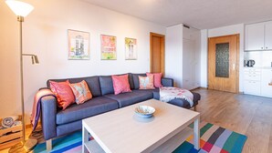 Ein modernes Wohnzimmer mit einer Couch, einem Couchtisch und einem durchgehenden Durchgang zur Küche.