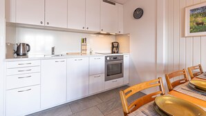 Eine moderne Küche mit weißen Schränken, einer Kaffeemaschine und einer Uhr an der Wand.