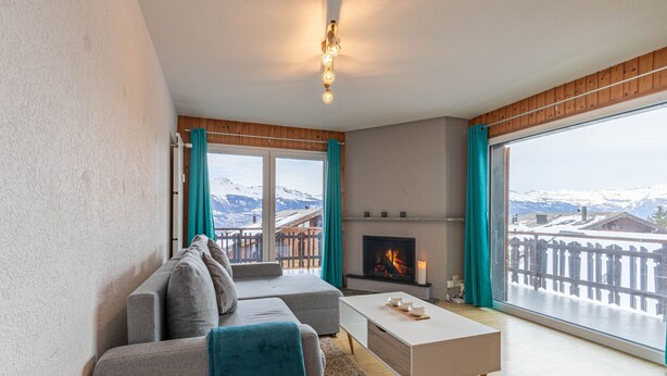 A living room with a sofa, a coffee table, a fireplace, and a large window with a view of mountains. - Mélèzes R 030 - SKI LIFT apartment 6 pers (Veysonnaz)