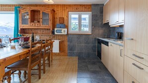 A wooden-paneled kitchen with a dining table, chairs, a microwave, and a window with a view. - Mélèzes R 030 - SKI LIFT apartment 6 pers (Veysonnaz)