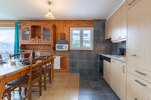 A wooden-paneled kitchen with a dining table, chairs, a microwave, and a window with a view. - Mélèzes R 030 - SKI LIFT apartment 6 pers (Veysonnaz)