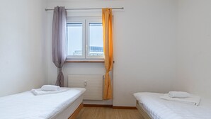 A small, clean room with two single beds, a window with curtains, and a radiator. - Mélèzes R 030 - SKI LIFT apartment 6 pers (Veysonnaz)