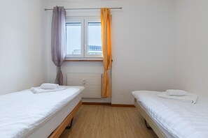 A small, clean room with two single beds, a window with curtains, and a radiator. - Mélèzes R 030 - SKI LIFT apartment 6 pers (Veysonnaz)