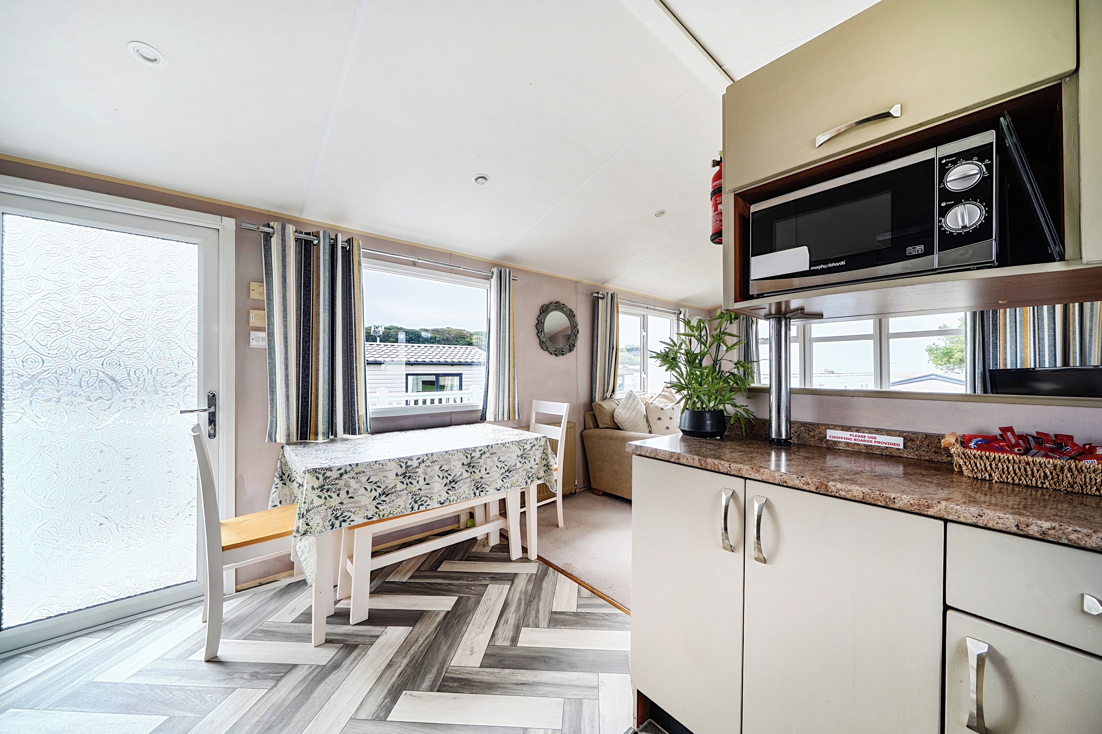 A modern kitchen with a dining area, large windows, and a herringbone floor pattern.