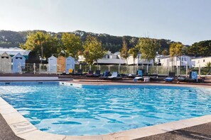 A swimming pool with lounge chairs and a view of houses and trees in the background. - Cabin Sleeps 8 - Pools, Parking, Pets (Weymouth)