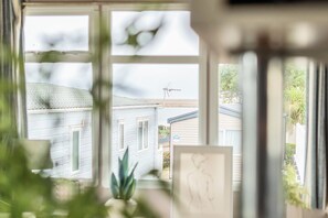 A view through a window with a house, a satellite dish, and a framed picture on the windowsill. - Cabin Sleeps 8 - Pools, Parking, Pets (Weymouth)