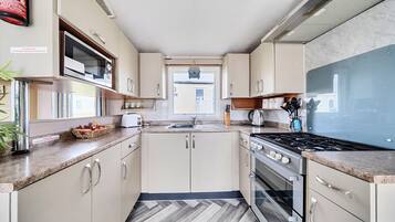 A compact kitchen with a microwave, stove, and sink.
