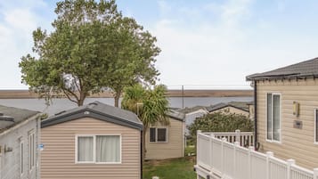 A row of mobile homes with a large tree in the foreground.