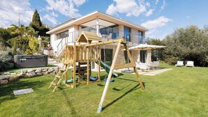 Una casa moderna con un parque infantil de madera en el patio.