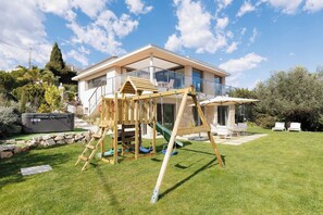 A modern house with a wooden play structure in the yard. - 🌿 Large Family Villa | Pool & Jacuzzi (Mougins)