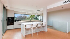 Una cocina moderna con una isla grande, taburetes de bar y vistas al exterior.