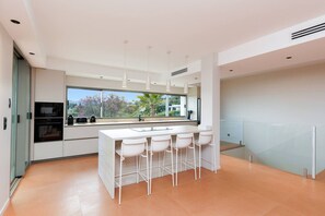 A modern kitchen with a large island, bar stools, and a view of the outdoors. - 🌿 Large Family Villa | Pool & Jacuzzi (Mougins)