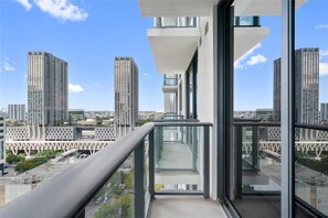 Ein Hochhaus mit einem Glasbalkon und Blick auf eine Stadtlandschaft.