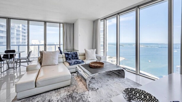 Una sala moderna con un sofá blanco, una mesa de centro y vistas al mar.