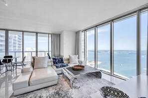 Una sala moderna con un sofá blanco, una mesa de centro y vistas al mar.