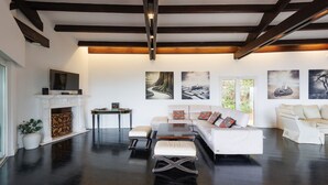 Uma sala de estar moderna com lareira, sofás brancos, uma mesa de centro e obras de arte nas paredes.