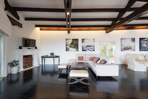 Ein modernes Wohnzimmer mit Kamin, weißen Sofas, einem Couchtisch und Kunstwerken an den Wänden.