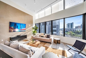 A modern living room with a sofa, coffee table, and a TV mounted on the wall. - District 225 • 2 BD/2BTH • City Views • Free Spa (Miami)
