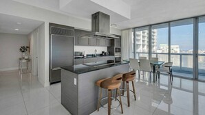 Een moderne keuken met een centraal eiland, barkrukken en een eethoek met uitzicht.