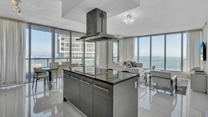 Een moderne keuken met een centraal eiland, grote ramen en uitzicht op de stad.