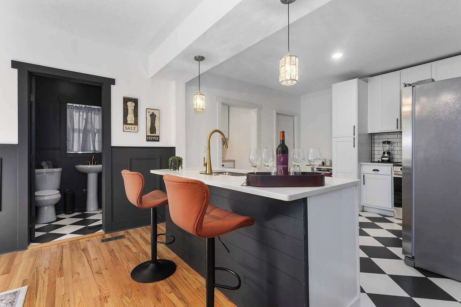 A modern kitchen with a bar area, a sink, and a wine bottle.