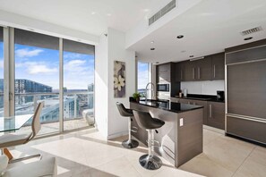 Una cocina moderna con una isla grande, taburetes de bar y vistas a la ciudad.
