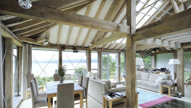 A spacious room with a high ceiling, large windows, a dining area, and a seating area with a view of the outdoors. - Tigh na Mara - Sleeps 4, Sea Views & Pet Friendly (Oban)