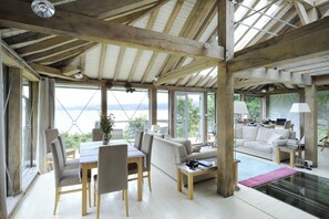 A spacious room with a high ceiling, large windows, a dining area, and a seating area with a view of the outdoors. - Tigh na Mara, Drimnin, Sea Views & Pet Friendly (Oban)