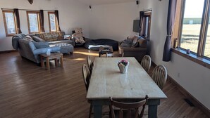 Un amplio espacio de sala con un sofá, una mesa de comedor y un ventanal grande.