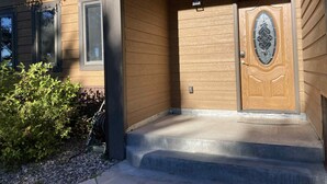 Una casa de madera con puerta principal, un pequeño porche y una ventana.