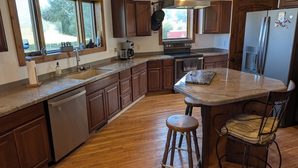 Una cocina con armarios de madera, un refrigerador de acero inoxidable, un horno empotrado y una ventana con vistas al exterior.