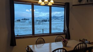 Un comedor con mesa y sillas, una ventana con cortinas y una araña.