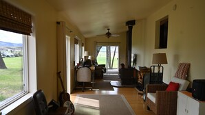 Uma sala de estar ampla com uma grande janela, um ventilador de teto e vista para o exterior.