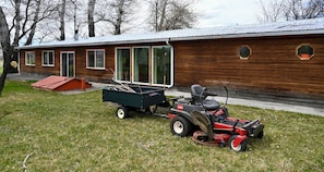 Ein Holzhaus mit großen Fenstern und einem Rasenmäher davor.