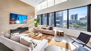 Ein modernes Wohnzimmer mit einer Couch, einem Couchtisch und einem an der Wand befestigten Fernseher.