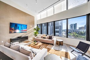 A modern living room with a sofa, coffee table, and a TV mounted on the wall. - District 225 • 2 BD/2BTH • 20th Fl • Free Spa (Miami)