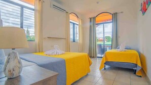 Una camera d'albergo con due letti, una lampada e vista sull'esterno.