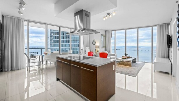 A modern kitchen with a central island, large windows, and a view of the sea. - Icon Brickell 2BR Ocean & Pool View + Spa Access (Miami)