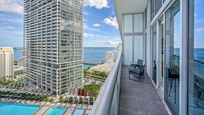 A high-rise building with a balcony featuring a pool, lounge chairs, and a view of the ocean. - Icon Brickell 2BDR 28th Fl Ocean Views+Spa Access (Miami)