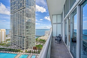 A high-rise building with a balcony featuring a pool, lounge chairs, and a view of the ocean. - Icon Brickell 2BDR 28th Fl Ocean Views+Spa Access (Miami)