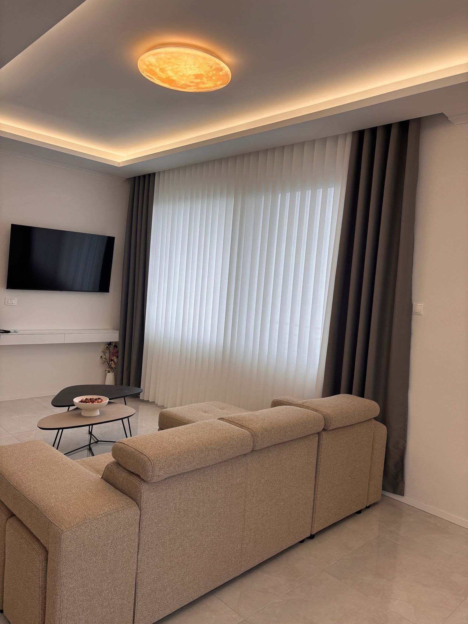 Un soggiorno moderno con un divano componibile, una televisione a schermo piatto e un'area pranzo con un tavolo e sedie.
