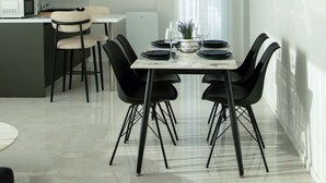Une cuisine moderne avec un coin repas, comprenant une table blanche mise avec des assiettes, des verres et un vase.