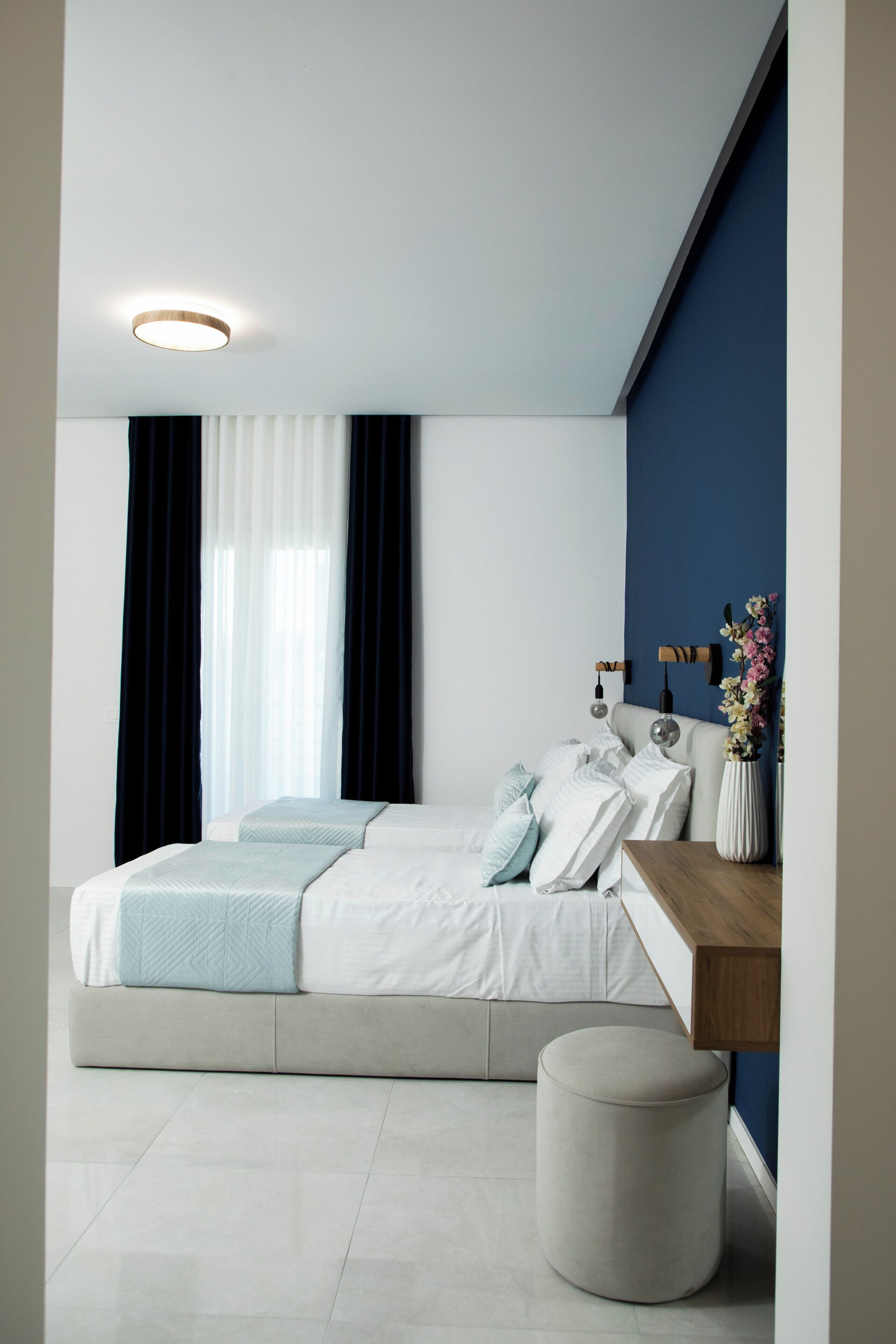 A modern bedroom with a bed, bedside table, and a round ottoman.