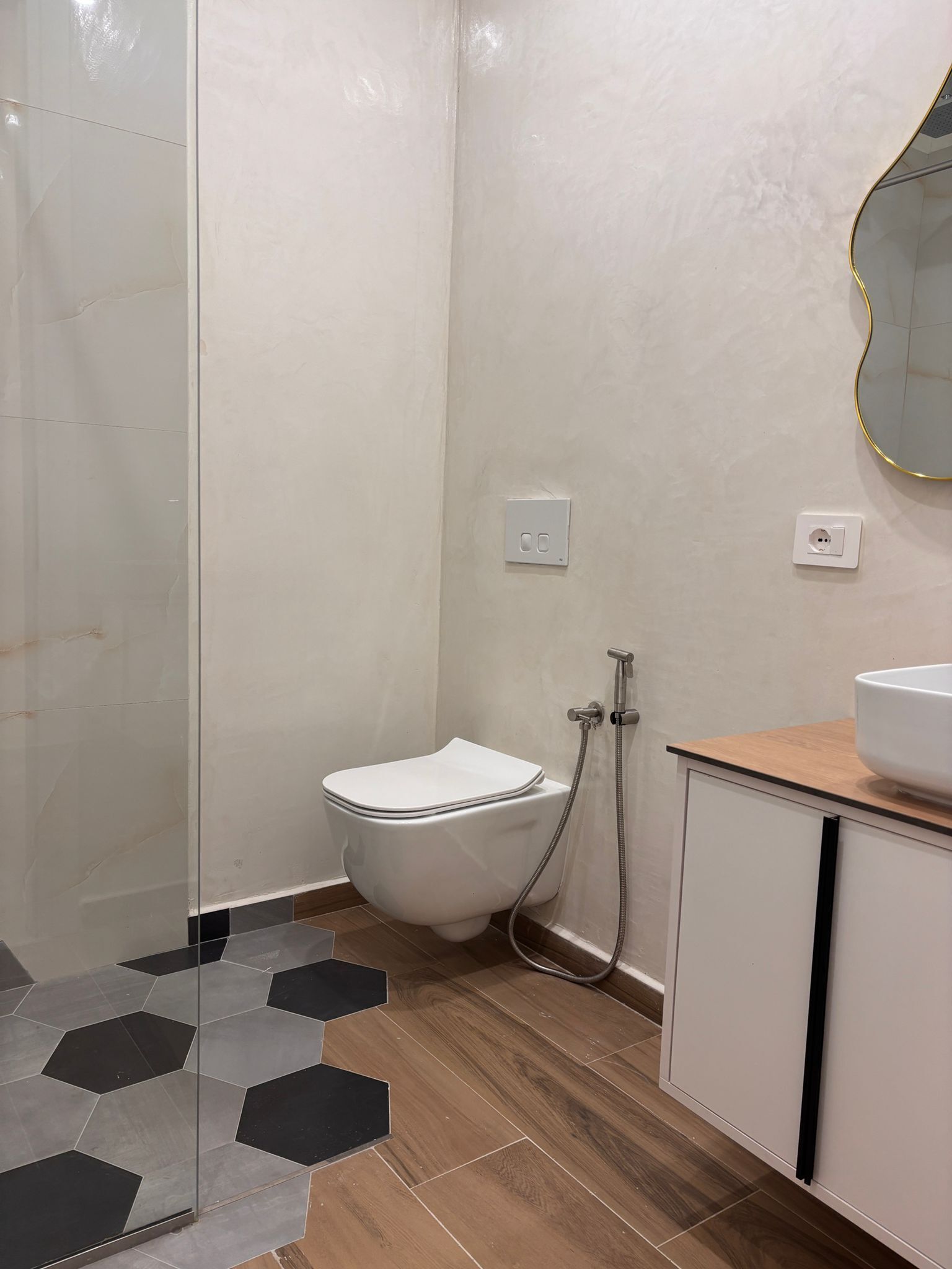 A bathroom with a toilet, shower, and sink.