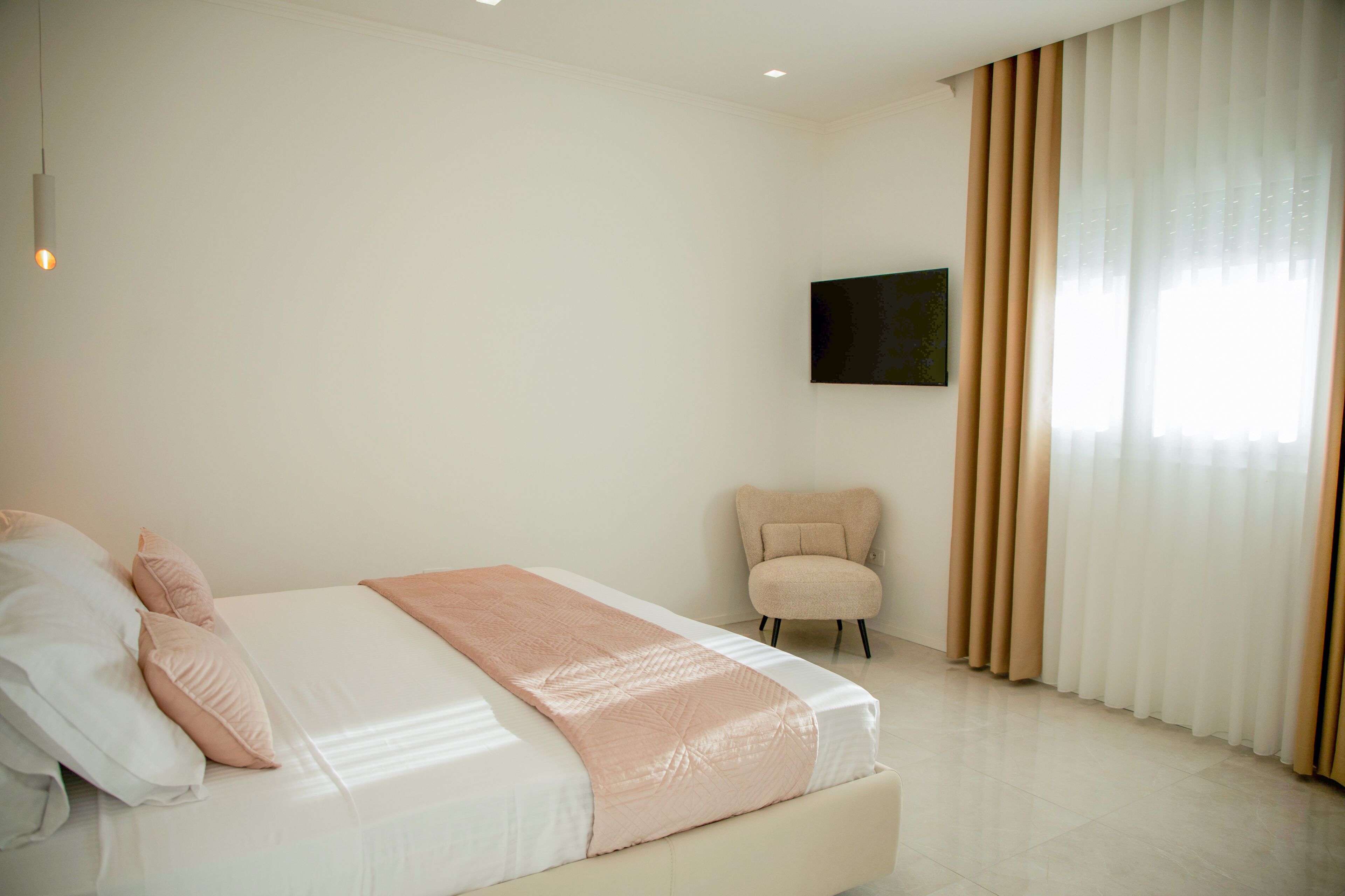 Une chambre à coucher avec un lit, une chaise, une télévision et des rideaux.