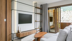 En moderne stue med et fladskærms-tv, træhylder, en hvid sofa og en stenvæg.