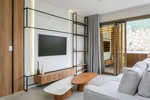 Ein modernes Wohnzimmer mit Flachbildfernseher, Holzböden, einem weißen Sofa und einer Steinwand.