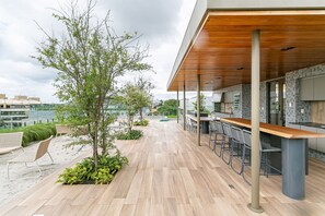 Ein moderner Außenbereich mit Holzboden, einer Bar und Blick auf die Stadt.
