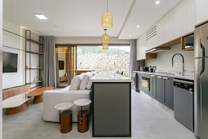 Eine moderne Küche mit einer Steinwand, integrierten Geräten und einer Sitzecke mit Sofa und Couchtisch.